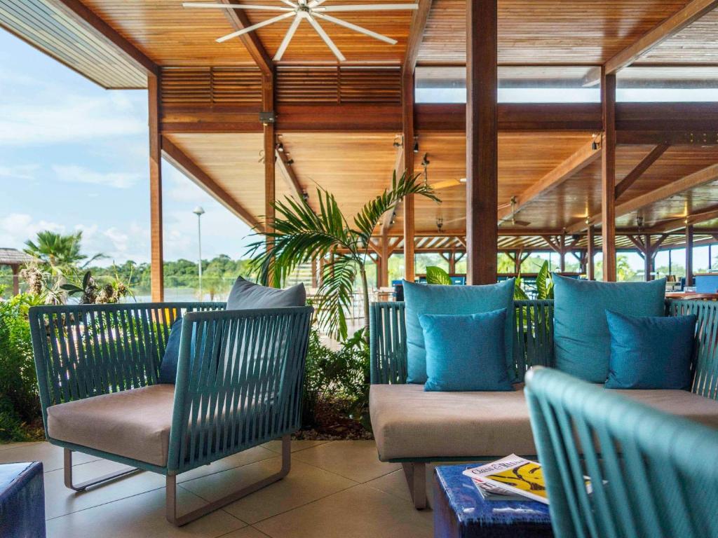 un patio con sillas y almohadas azules. en Hotel Mercure Kourou Ariatel, en Kourou