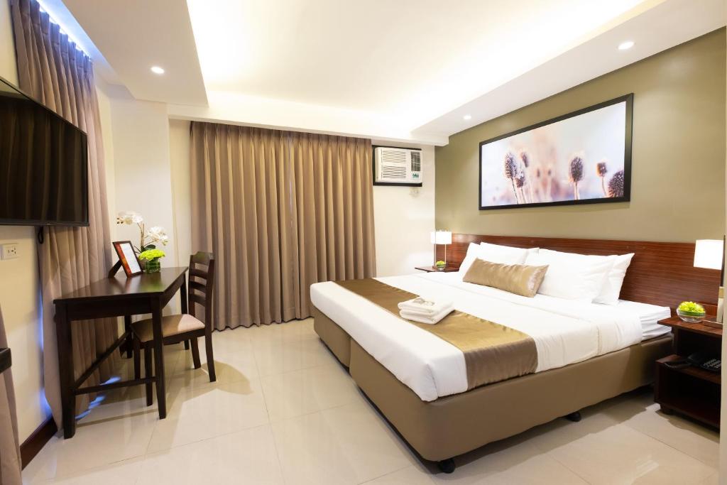a hotel room with a large bed and a desk at Soleil Suites Cebu in Cebu City