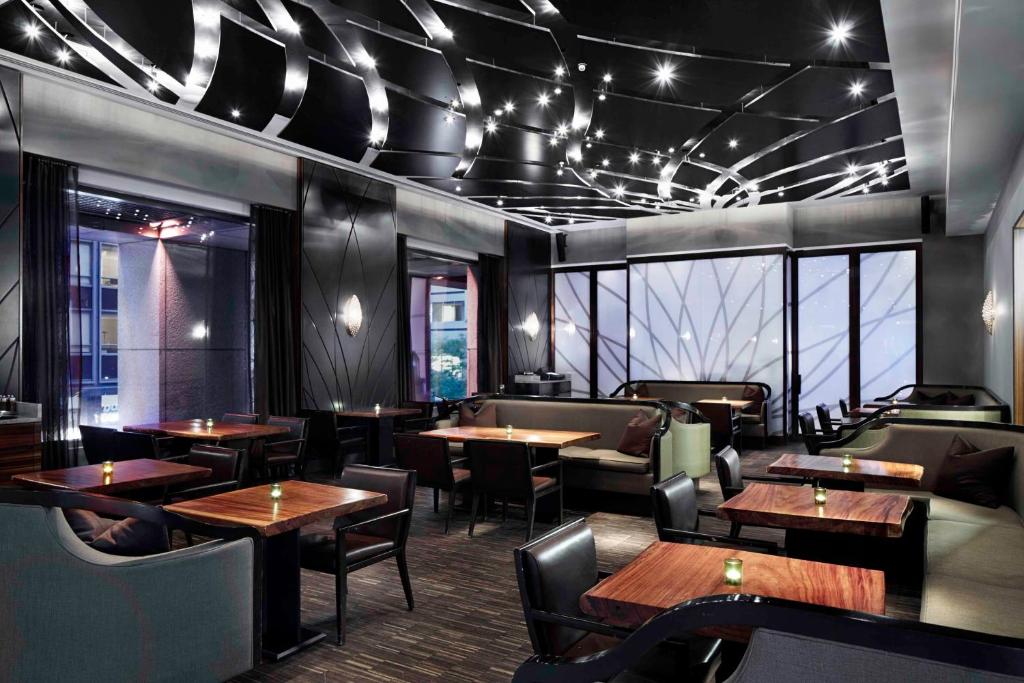 a restaurant with wooden tables and chairs and windows at Hyatt Centric Wall Street New York in New York