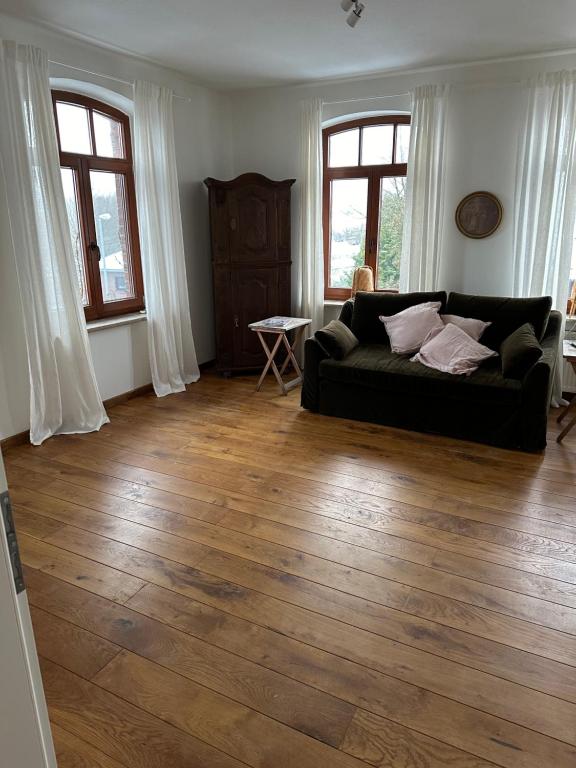 a living room with a black couch and wood floors at Kuschelige Ferienwohnung auf Reiterhof 