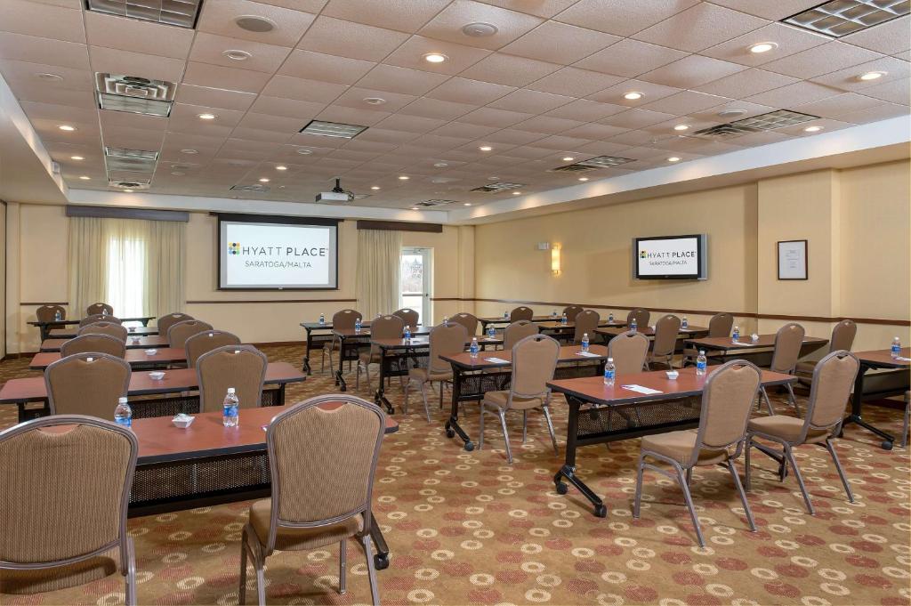 a conference room with tables and chairs and a projection screen at Hyatt Place Saratoga/Malta in Malta