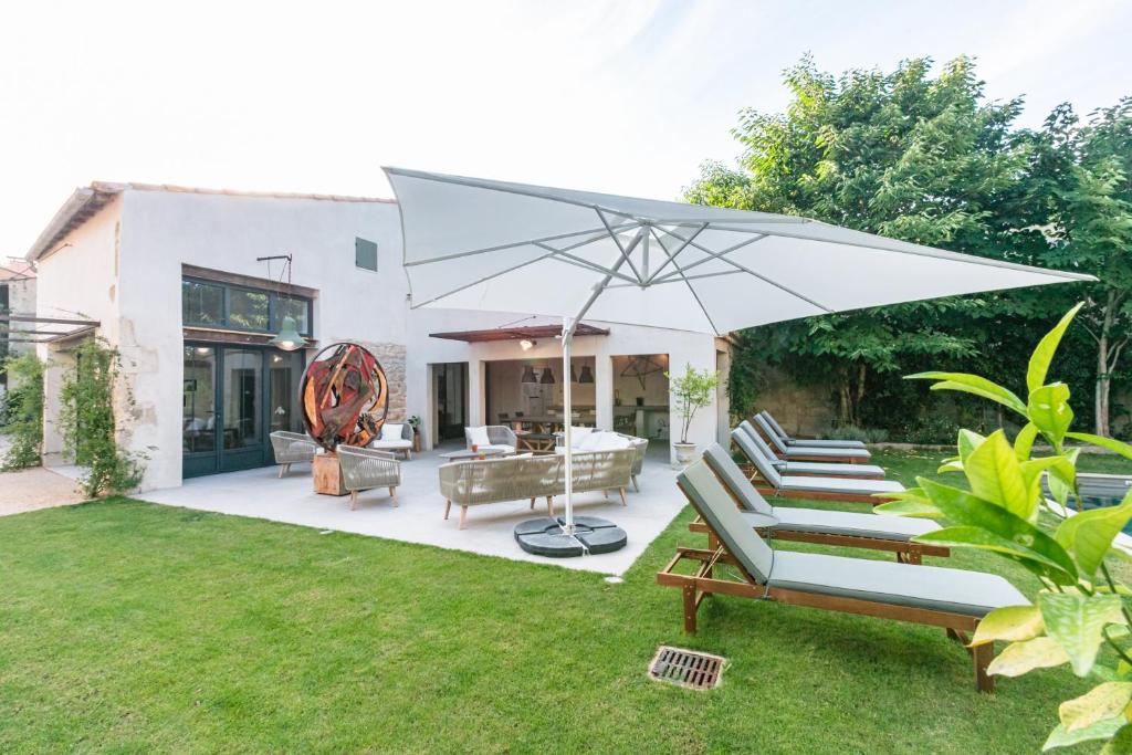 eine Terrasse mit Liegestühlen und einem Sonnenschirm in der Unterkunft Gabrielle Jeanne in Maillane