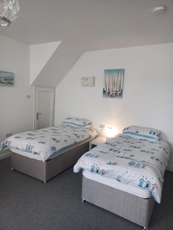 two twin beds in a room with white walls at Sea Breeze Studio @ The Coach House in Saint Annes on the Sea