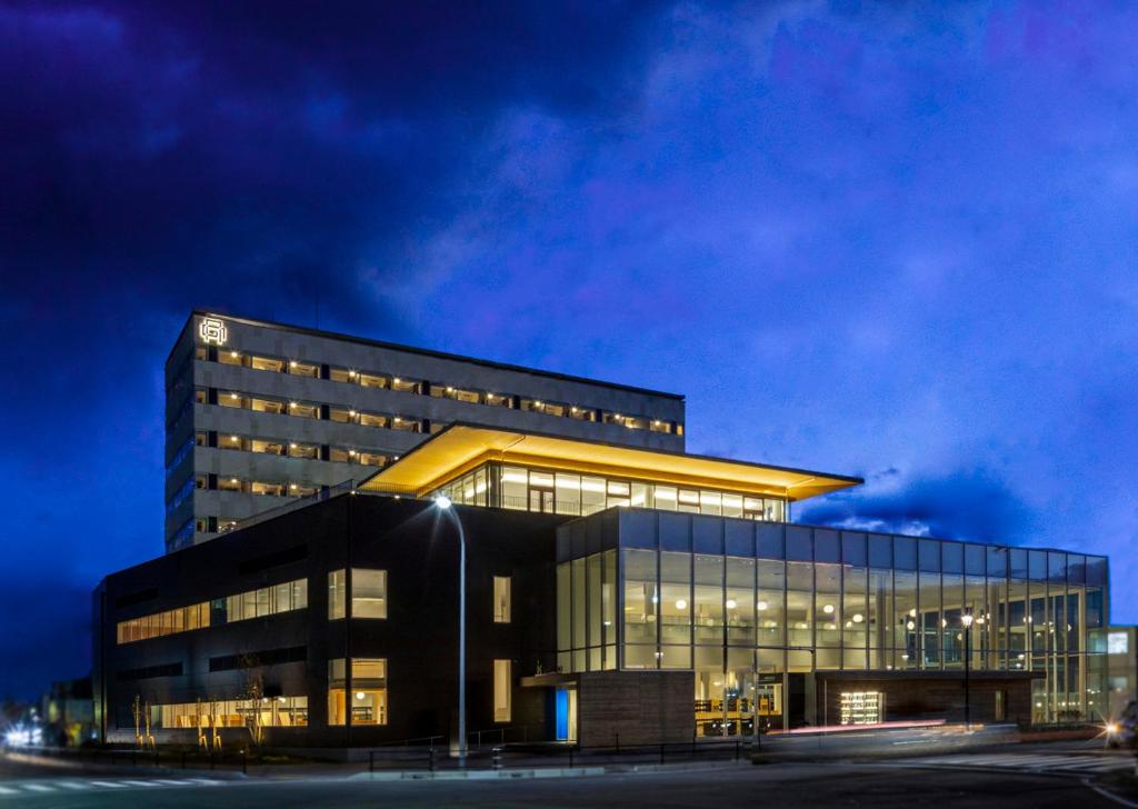 un gran edificio de oficinas con una fachada iluminada por la noche en Tsukino HOTEL en Sakata