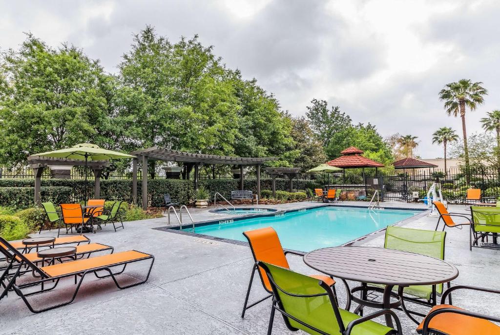 una piscina con mesas y sillas junto a una piscina en La Quinta by Wyndham Tomball, en Tomball