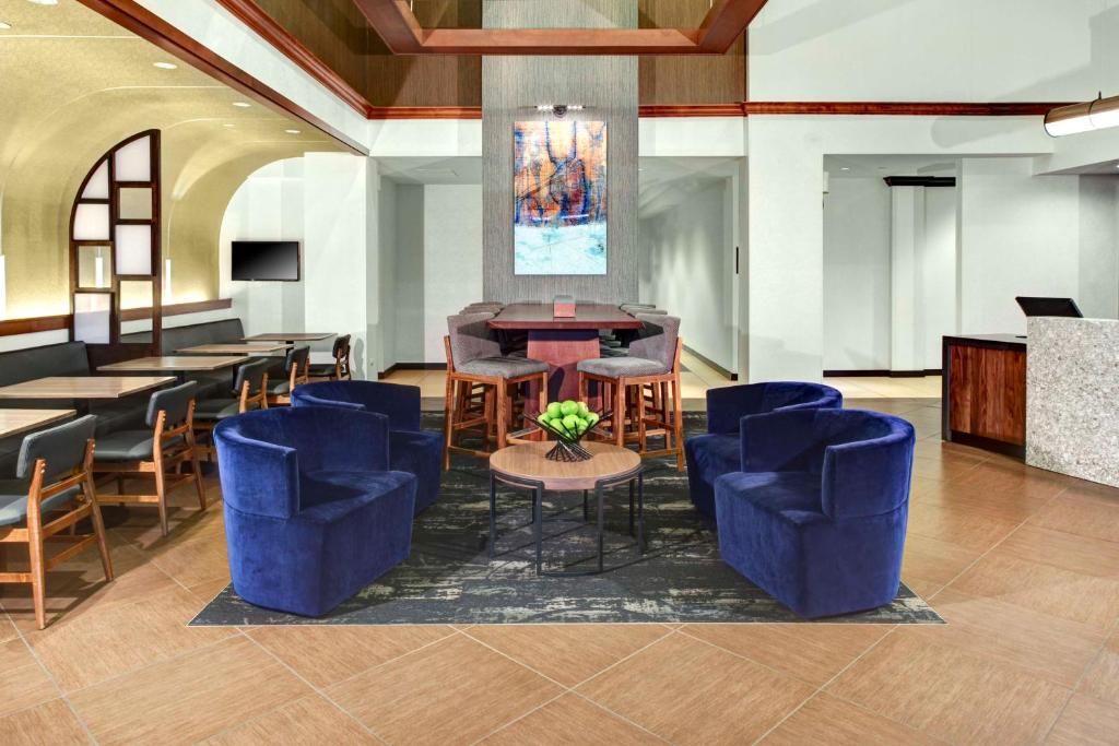 a lobby with blue chairs and a table and a bar at Hyatt Place Atlanta / Norcross / Peachtree in Norcross