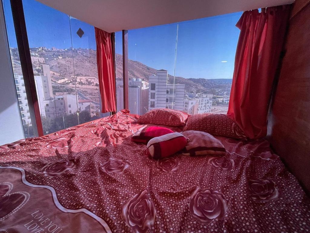 a bed in a room with a view of a city at cabin hotel in Ma‘ān