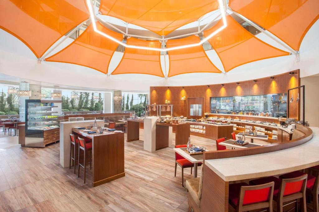 a restaurant with an orange ceiling and tables and chairs at Hyatt Place Hyderabad Banjara Hills in Hyderabad
