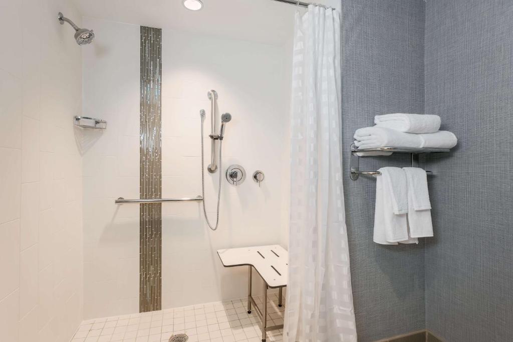 uma casa de banho com chuveiro, WC e toalhas em Hyatt Place Austin Cedar Park em Cedar Park