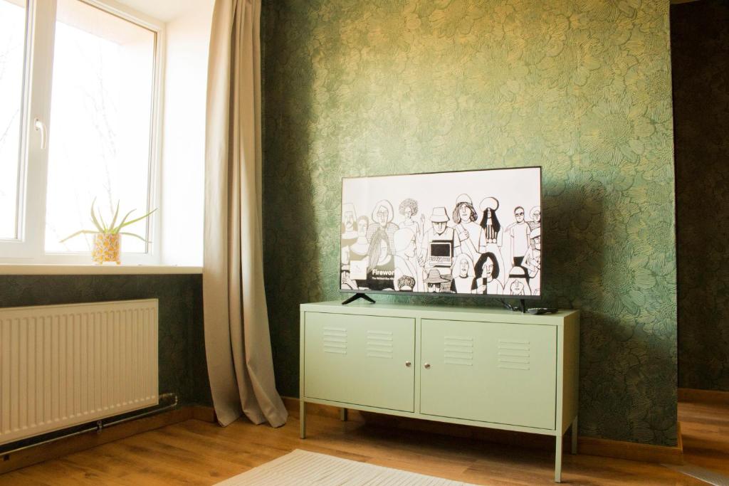 a living room with green wallpaper and a tv on a cabinet at Gaujas naktsmājas in Valmiera