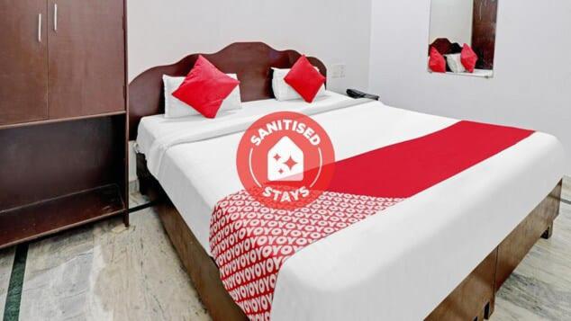 a bed with a red and white comforter on it at Backpackers Dinesh Home Stay in Khajurāho
