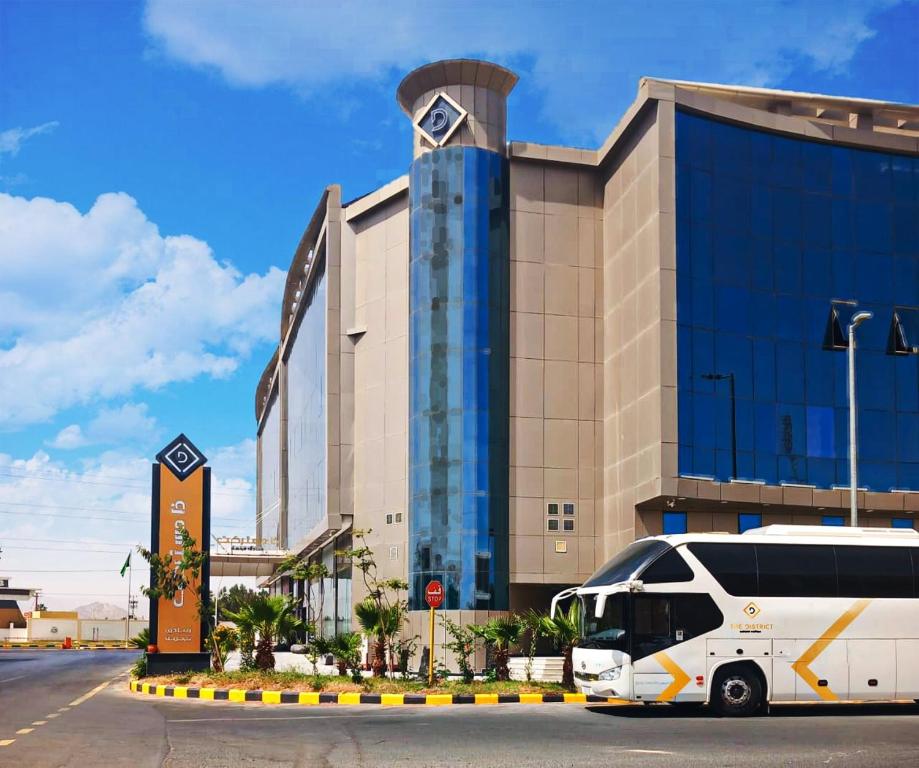 a white bus parked in front of a building at The District Hotel Najran in Najran