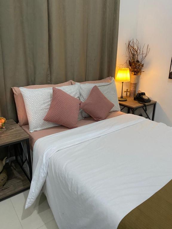 a bed with pink and white pillows on it at Deluxe studio unit at Modena Town Sq in Tunghaan