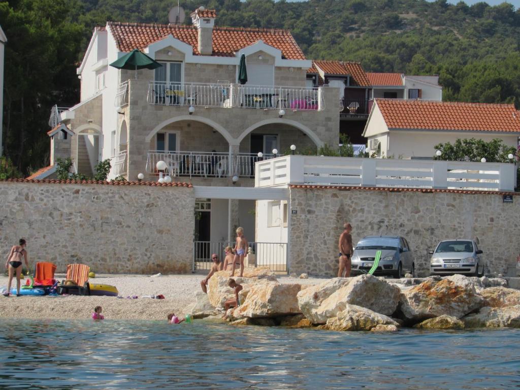 a group of people on the beach in front of a house at Bonacic Palace in Slatine