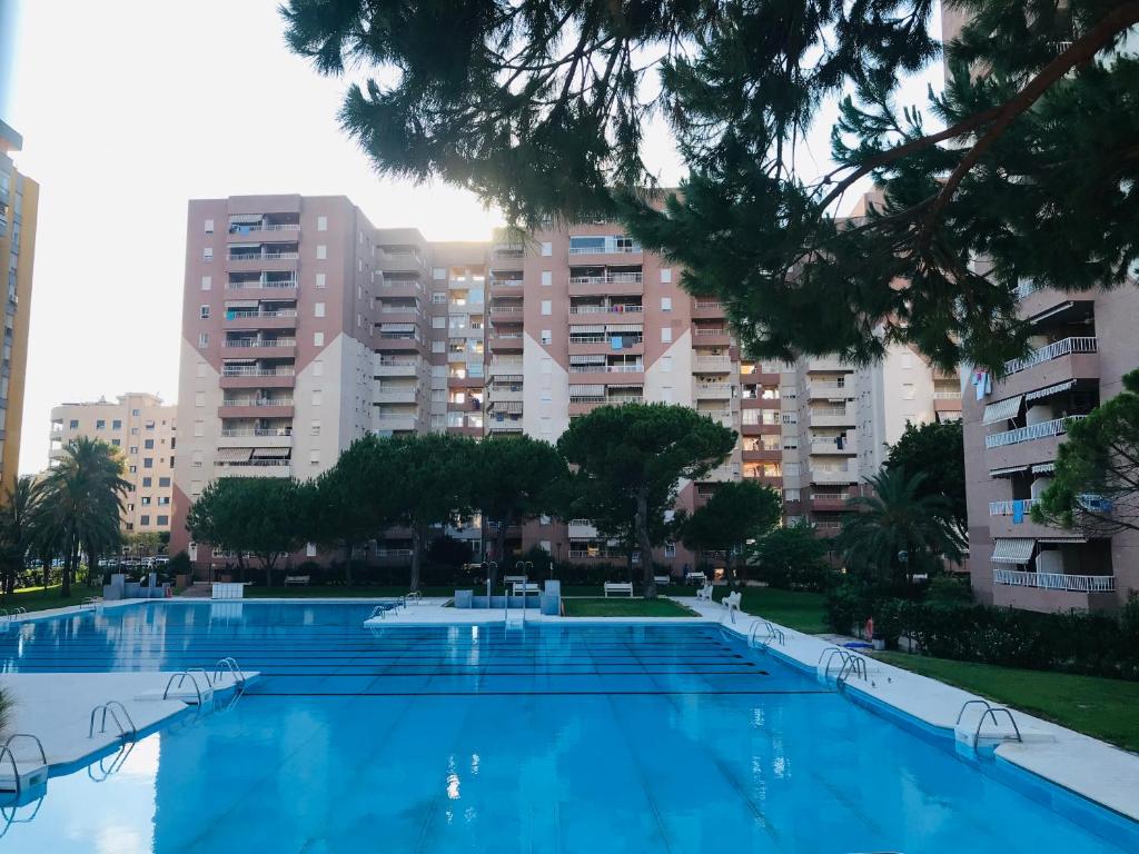 Apartamento en la Playa Canet, muy cerca de Valencia في كانيت ذي بيرينغير: مسبح كبير وبه مباني في الخلف