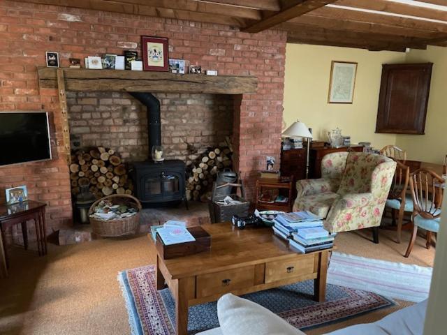 a living room with a fireplace and a table and a couch at The Old Coach House in Cheltenham