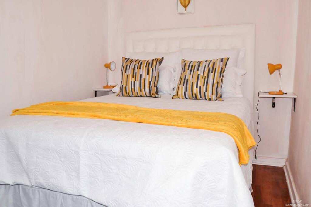 un letto bianco con una coperta gialla sopra di Sunflower Cottage 15min from OR Tambo a Johannesburg