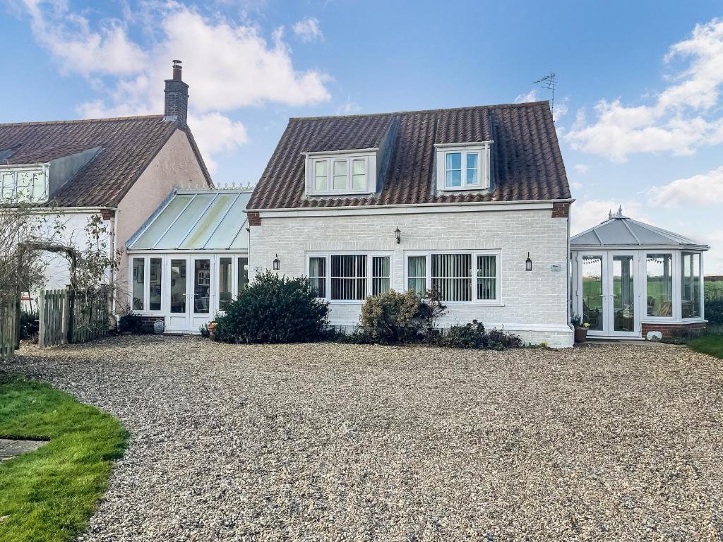 a white house with a large gravel driveway at Iris Apartment in Stalham