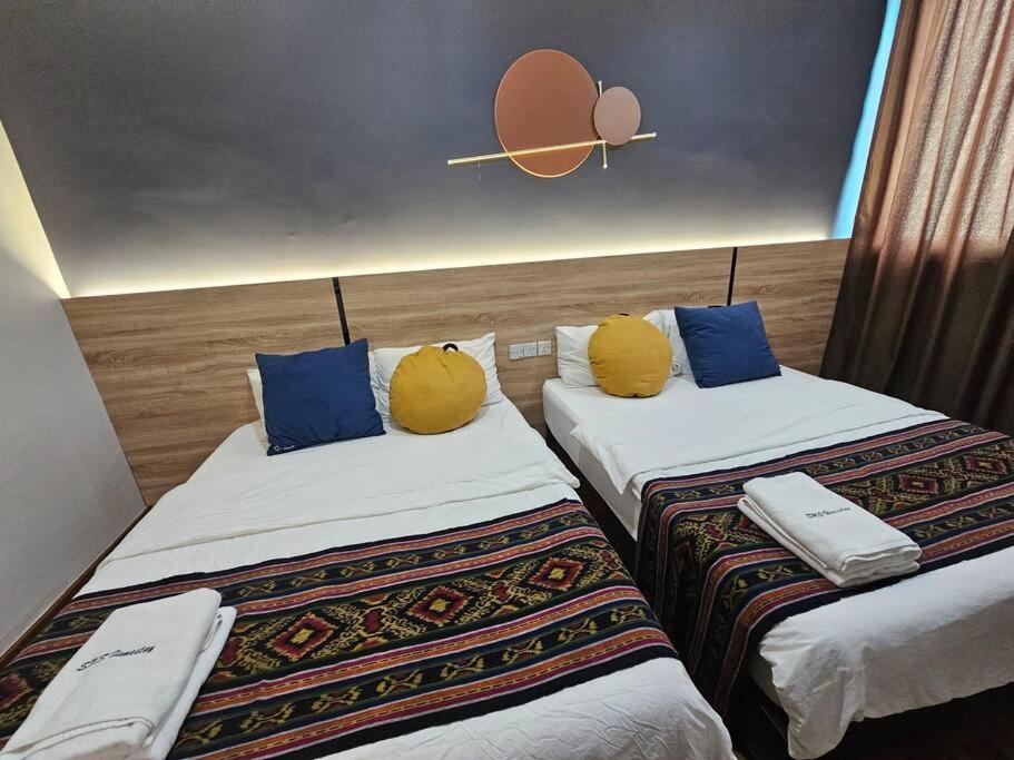 two beds with yellow pillows in a hotel room at Vivacity Jazz 1 Luxury Cozy Home 8paxs Card LV 12 in Kuching
