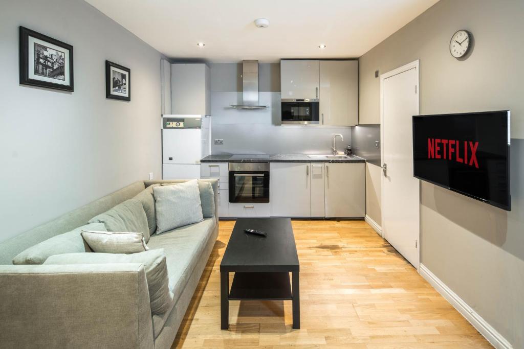 ein Wohnzimmer mit einem Sofa und einer Küche in der Unterkunft Cosy 2-Beds, Shepherd Bush in London