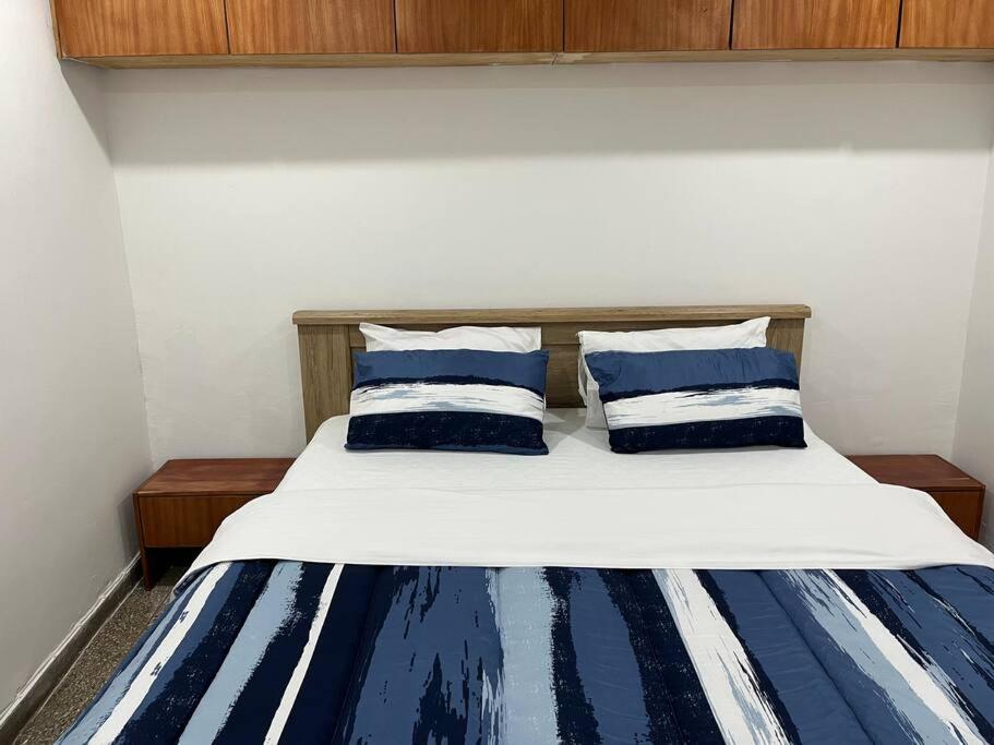 a bed with two blue and white pillows on it at Lx Apart in Sommerschield 2 in Maputo