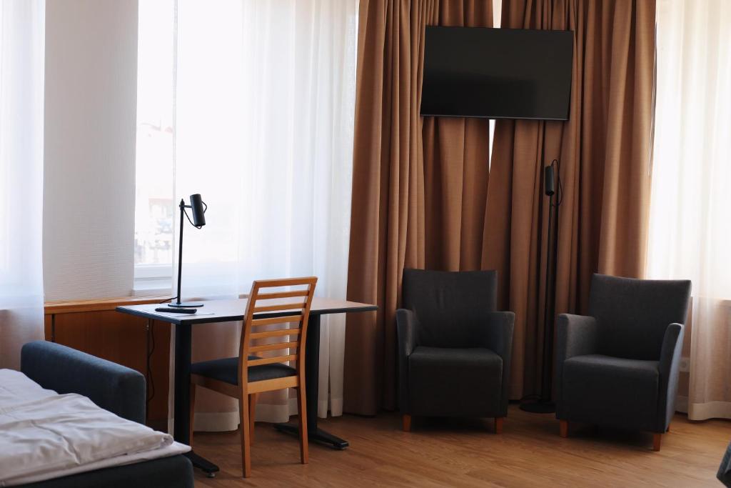 a room with a desk and two chairs and a bed at Hesehotelli Turku Linja-autoasema in Turku