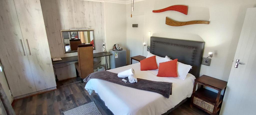 1 dormitorio con 1 cama grande con almohadas rojas en Premiere Guesthouse, en Bloemfontein