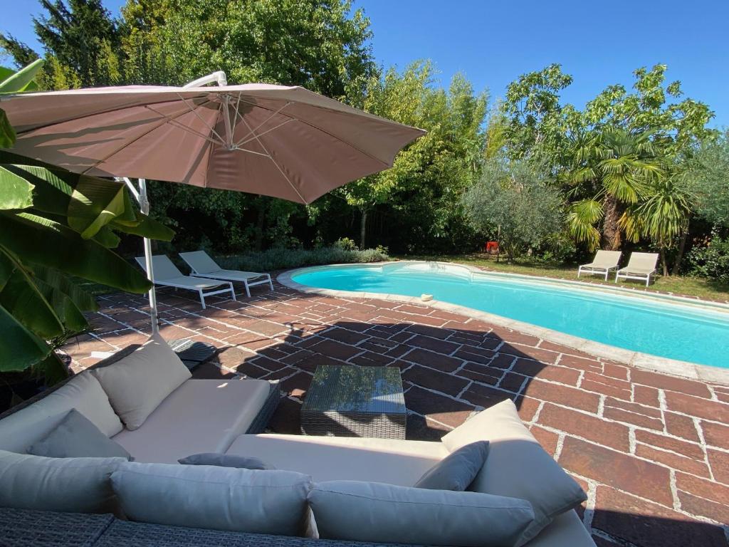 特雷拉澤的住宿－Chez Alix et Christophe，一个带沙发和遮阳伞的庭院,毗邻一个游泳池
