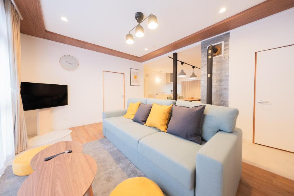 a living room with a blue couch with yellow pillows at Furano Powder Chalet in Furano