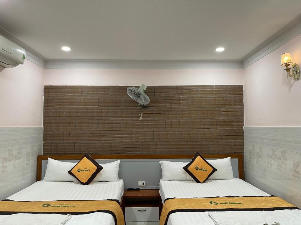 Ðông HòaにあるHương Thiên Phú Hotelのベッドルーム1室(ベッド2台、壁にファン付)