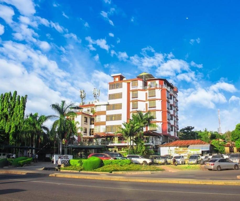 ein hohes Gebäude mit Autos auf einem Parkplatz in der Unterkunft Hotel Kingdom in Mwanza