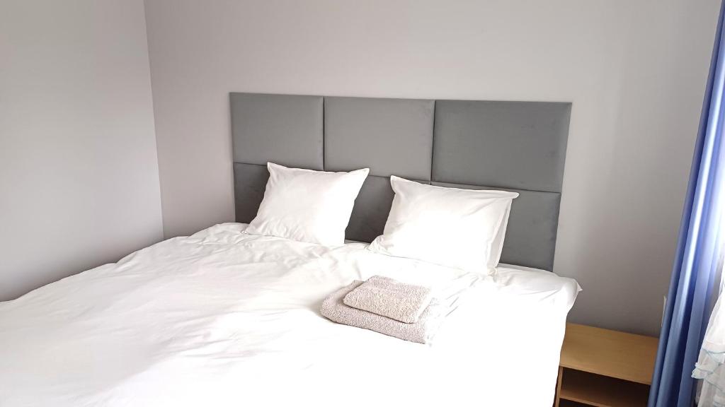 1 cama con sábanas blancas y cabecero gris en Matylda House, en Cracovia