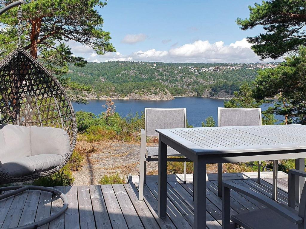 a table and chairs on a deck with a view of a lake at Holiday home Risør in Risør