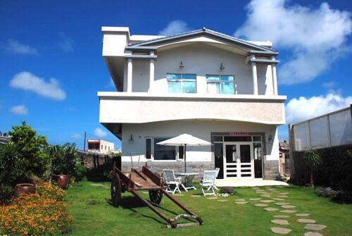 a white house with a table and chairs in a yard at Blue Lagoon in Huxi