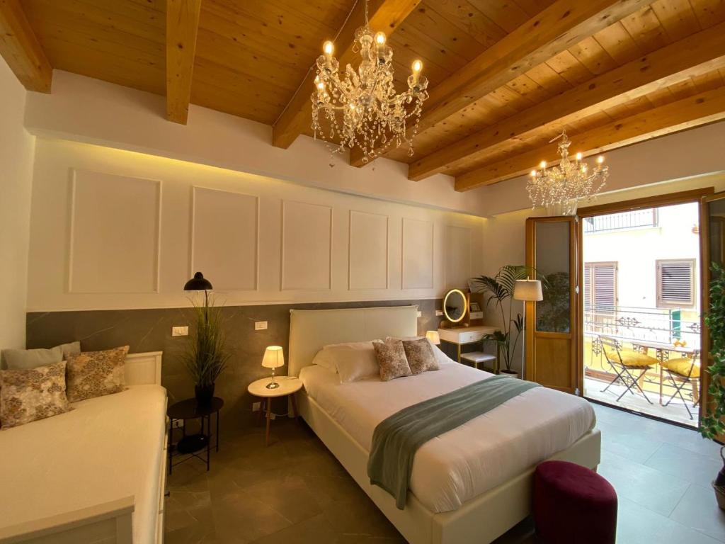 a bedroom with a bed and a couch and a chandelier at Atrium in Castellammare del Golfo