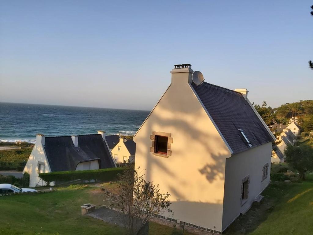 une maison blanche avec un toit noir à côté de l'océan dans l'établissement 707 -Maison de charme au Domaine privée De Lanruen, à Erquy