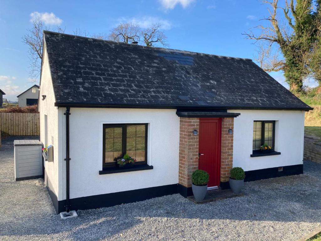 ein kleines weißes Haus mit einer roten Tür in der Unterkunft Joe’s Cottage in Tynan
