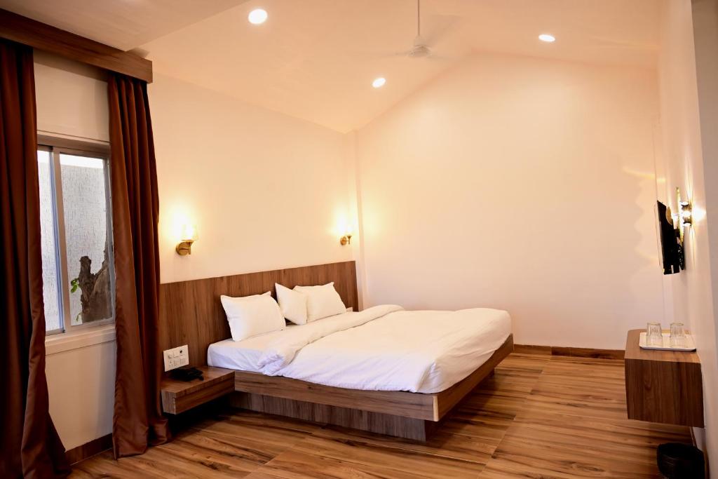 a bedroom with a bed with white sheets and a window at The Serene Woods Resort in Matkuli