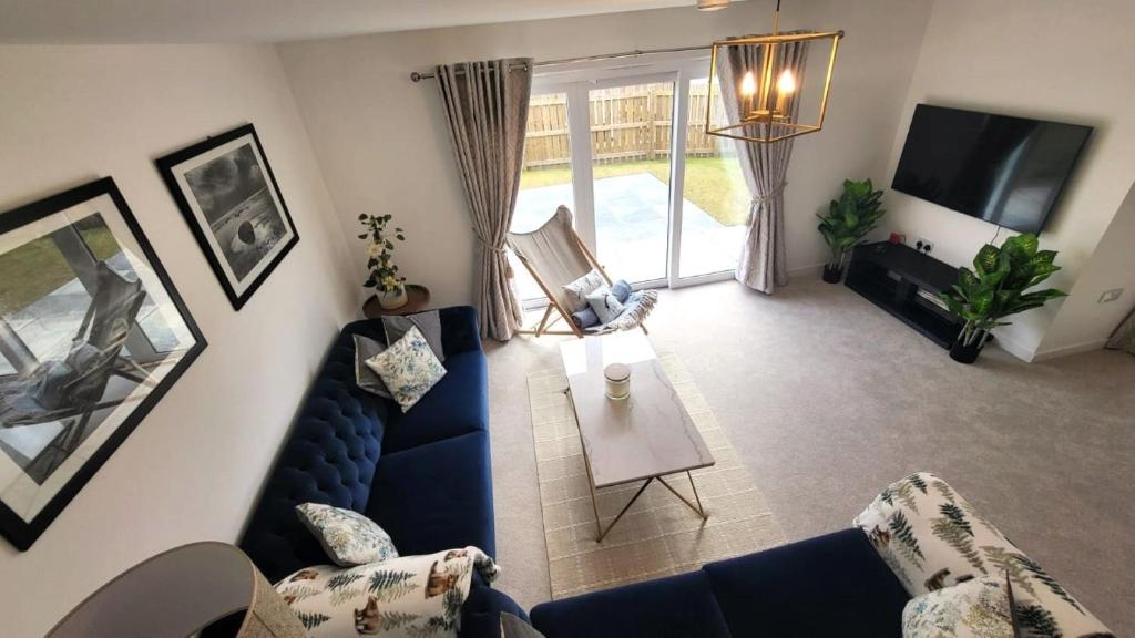 uma sala de estar com um sofá azul e uma televisão em Insch House em Kincraig