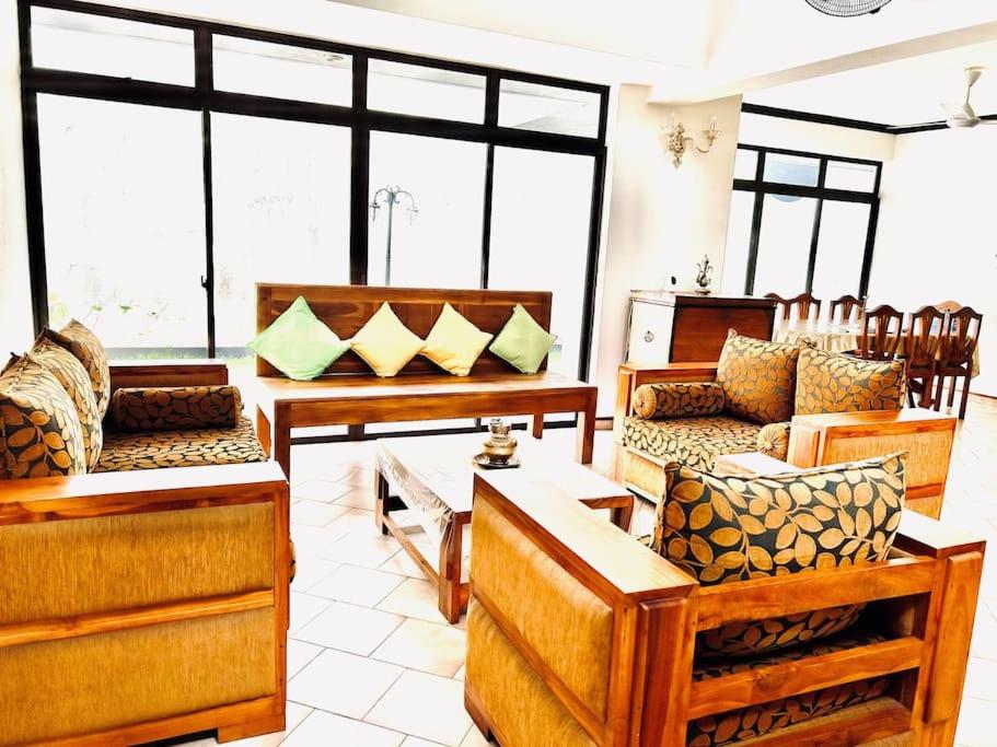 ein Wohnzimmer mit Holzmöbeln und großen Fenstern in der Unterkunft VILLA COLOMBO7 5BR HOLIDAY HOME UP to 10 Guests in Colombo