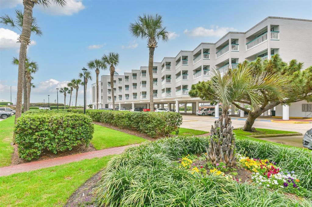 un gran edificio de apartamentos con palmeras y un jardín en Tipsea on the seawall, en Galveston