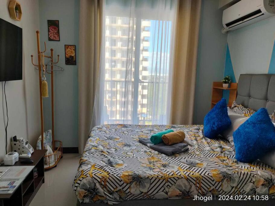 a bedroom with a bed with blue pillows and a window at Mister Ghrays Hub in Lapu Lapu City