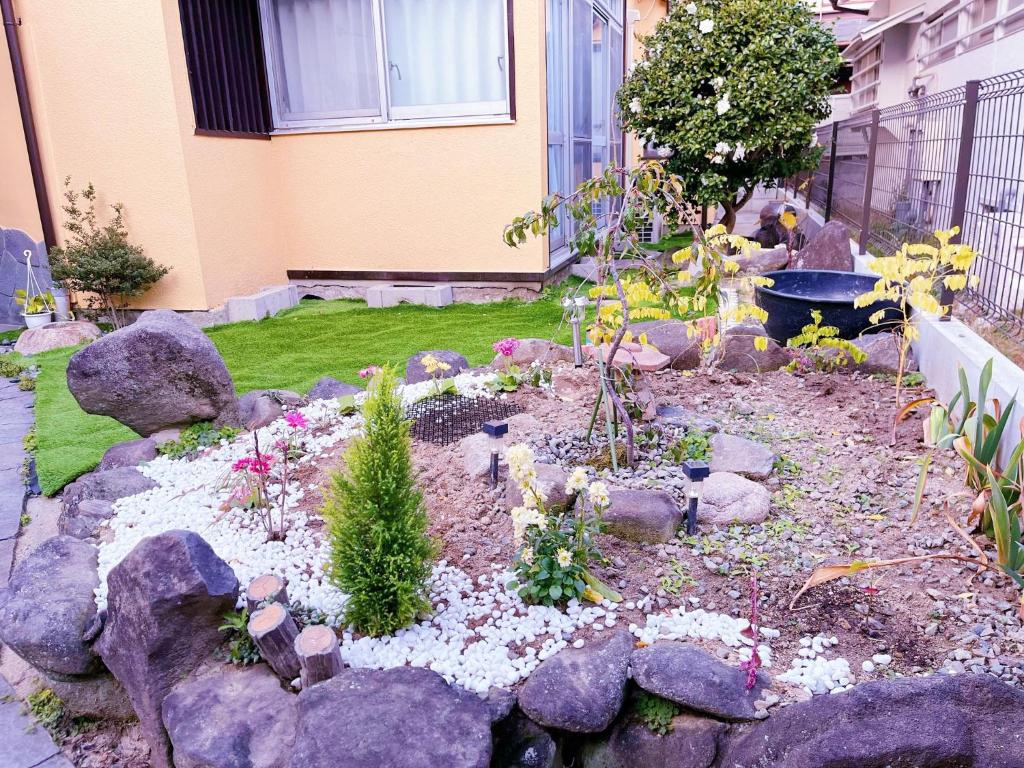 豐中的住宿－Otami Stay，一座花园,在房子前面有岩石和植物