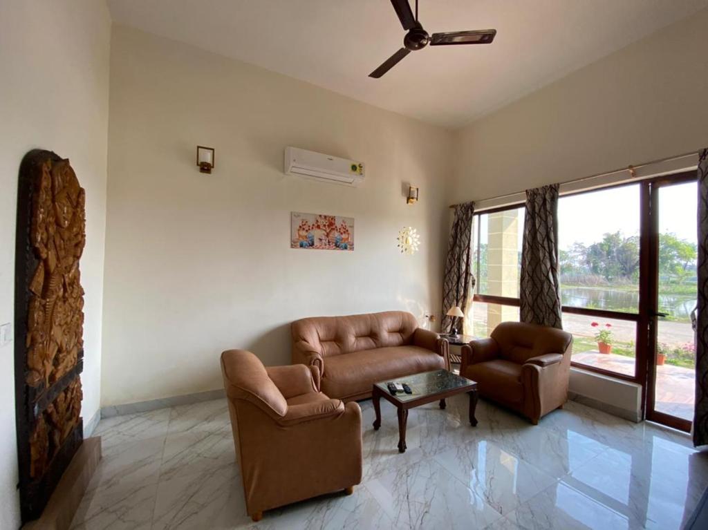 a living room with leather furniture and a large window at Aqua villa vedic village in kolkata