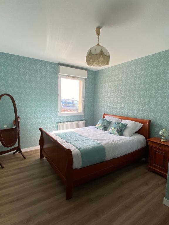 Schlafzimmer mit einem Bett mit blauen Wänden und einem Fenster in der Unterkunft Appartement Thème Années 20, proche du Puy Du Fou in Pouzauges