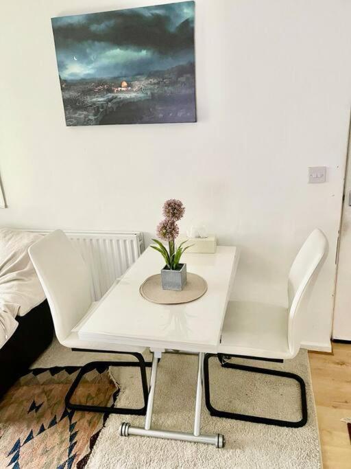 a white table and chairs with a potted plant on it at One Bed Flat by Colindale Tube station in Colindale
