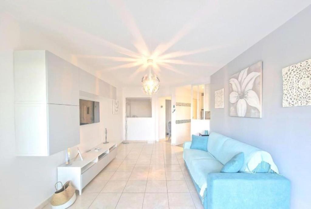 un salon avec un canapé bleu dans une pièce dans l'établissement Rez de Jardin port santa lucia, à Saint-Raphaël