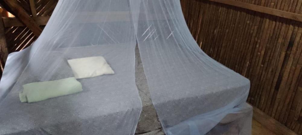 a bed with a net with two pillows on it at Hospedaje Agroturismo Wounaan in Pidiaque