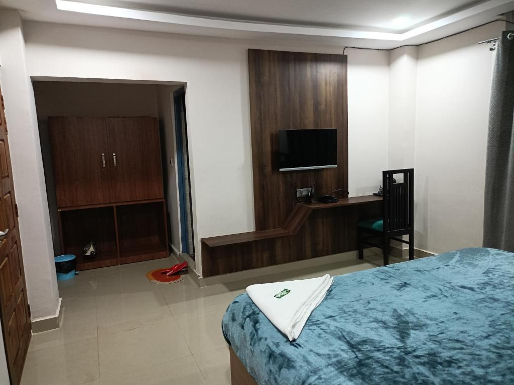 a bedroom with a bed and a desk and a television at Hilsan Hotel in Bomdila