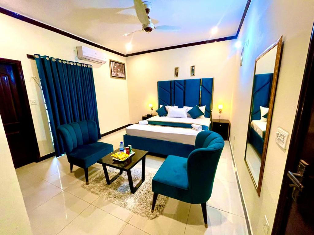 a bedroom with a bed and two chairs and a table at Go Guest House Lahore in Lahore